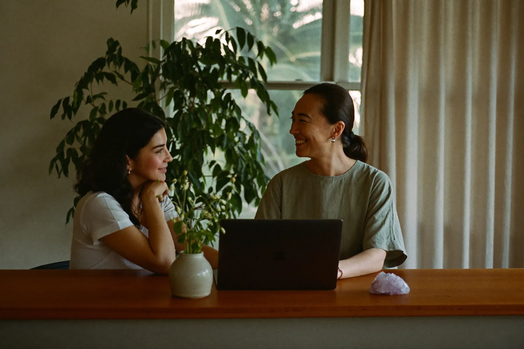 A wellness practice owner and a consultant smiling together over a laptop at the front desk